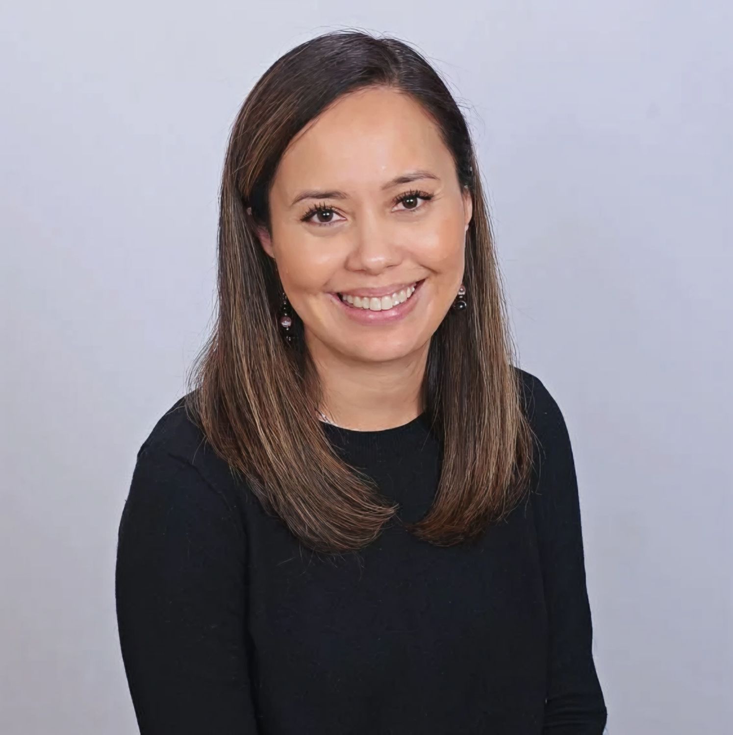 Smiling woman in a black shirt, neutral background.