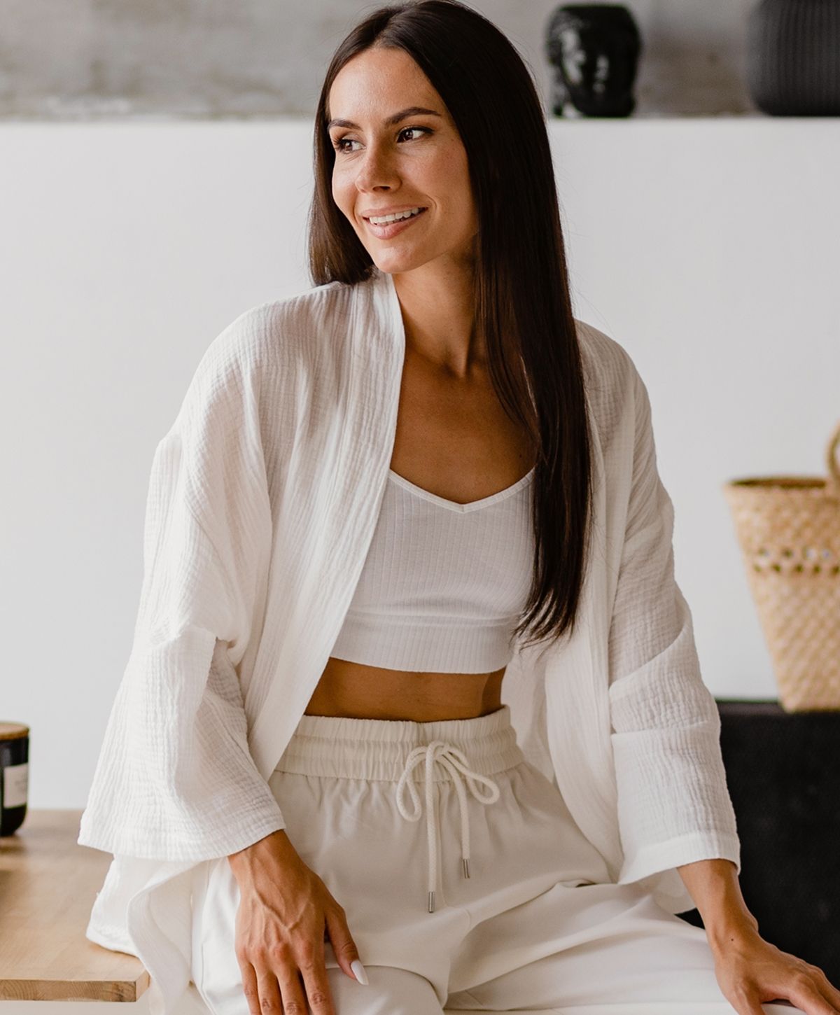 Woman in stylish white outfit, smiling softly.