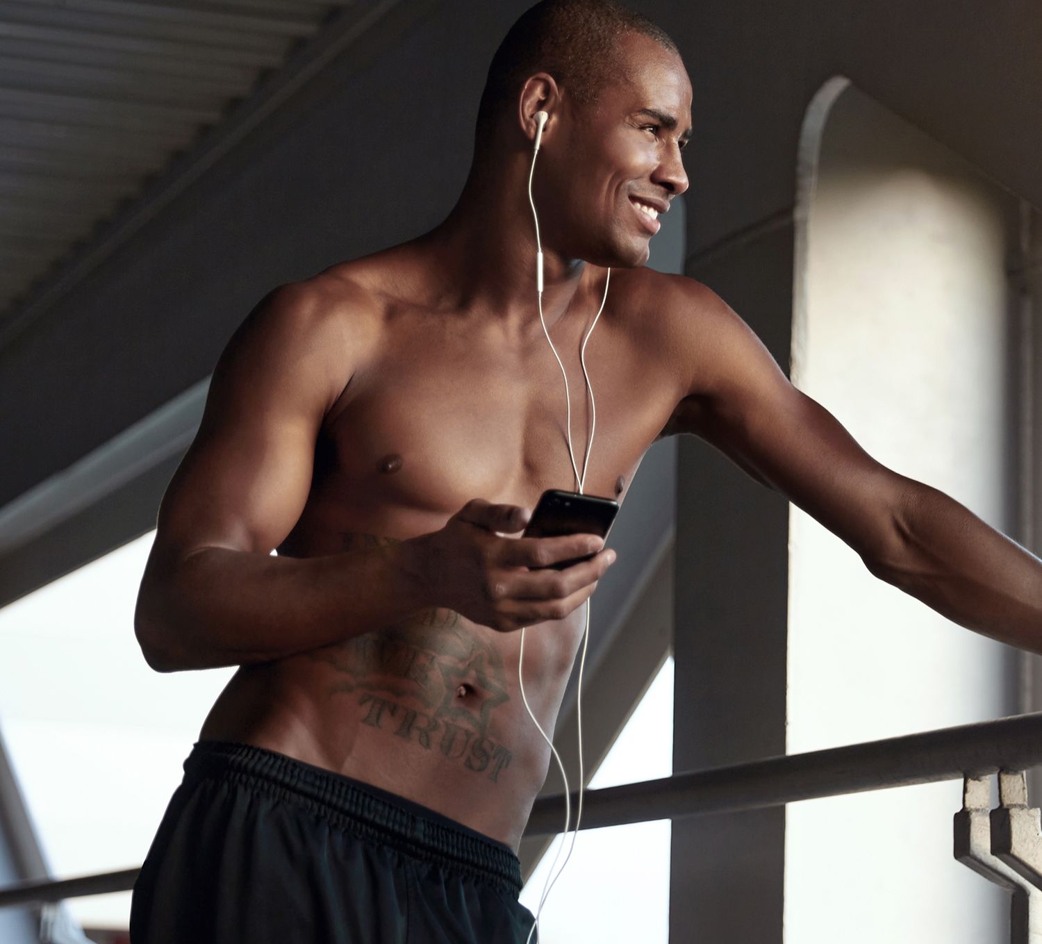 Man smiling, wearing earphones, holding phone.
