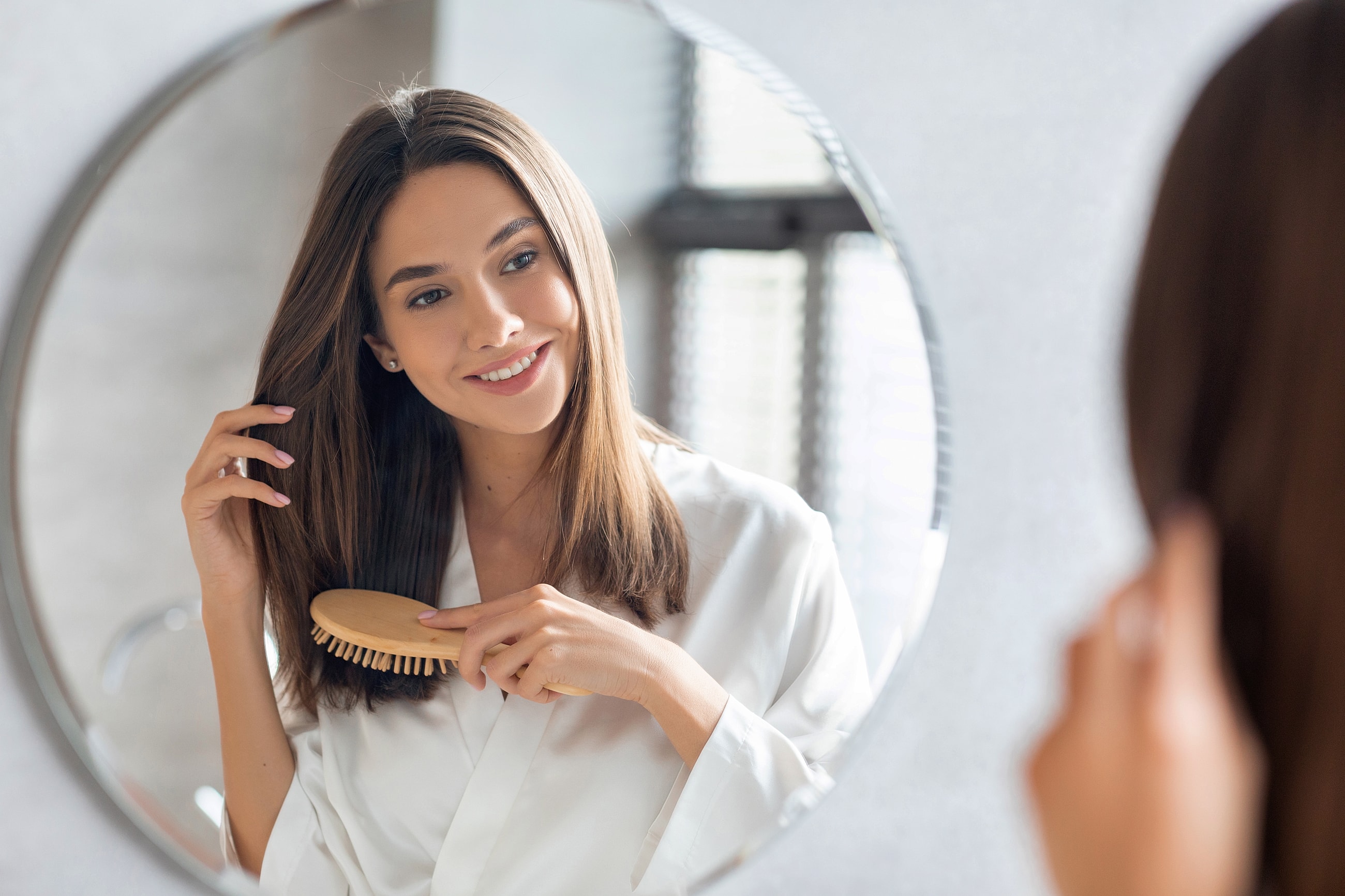 Woman brushing hair in front of mirror.