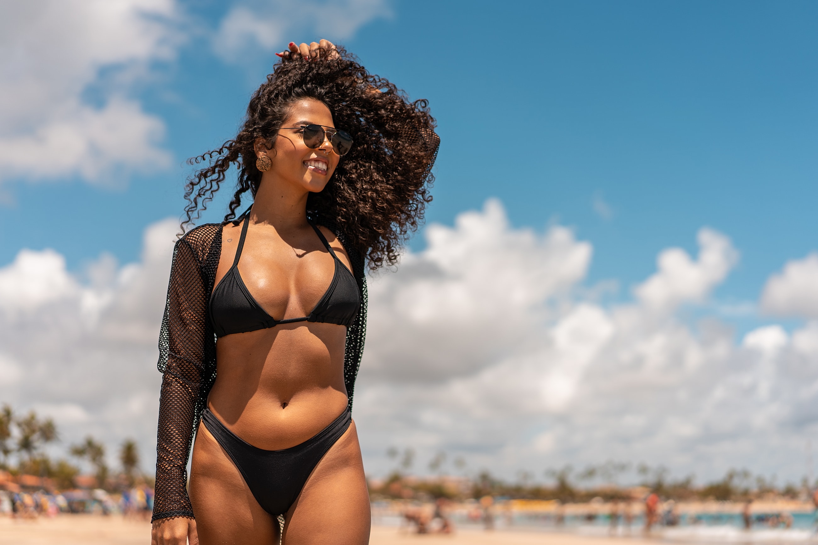 Woman in black bikini enjoying sunny beach day.