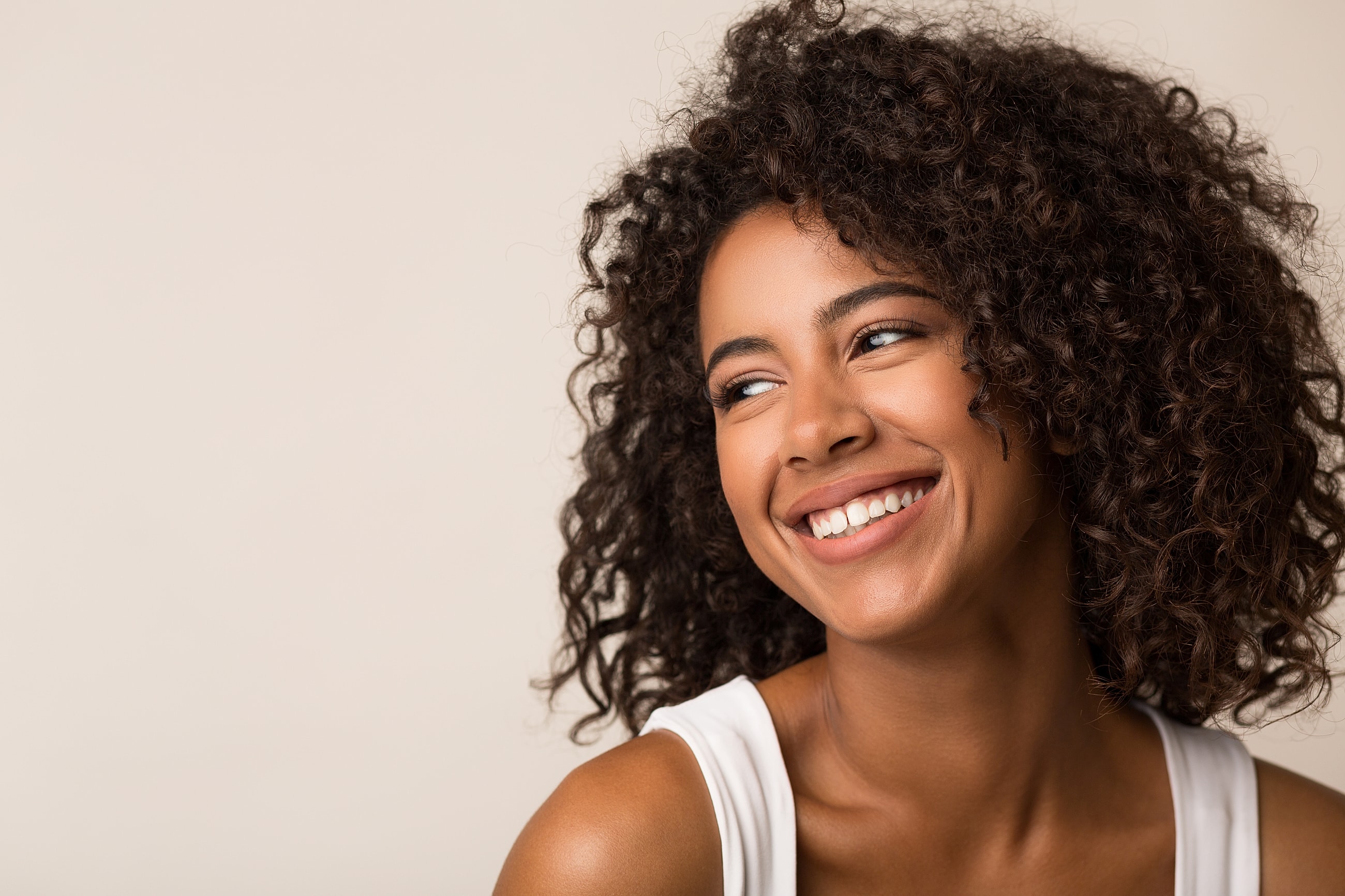 Smiling woman with curly hair and joyful expression.